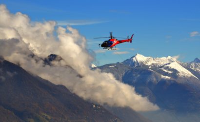 helicopter flying among clouds snow capped mountains 1