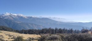 A wide, scenic view of the mountain range with snow-capped peaks and clear blue sky.