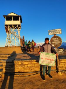 Person holding sign at Poonhill standing Infront of Landmark the at Poonhill point