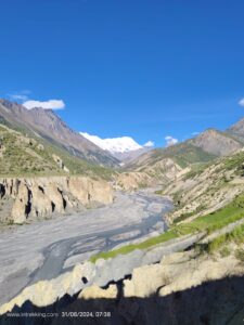 River flowing through a mountain valley under a blue sky. 