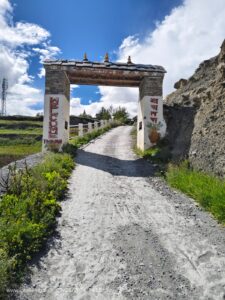 Stone archway on a dusty road in mountainous region.