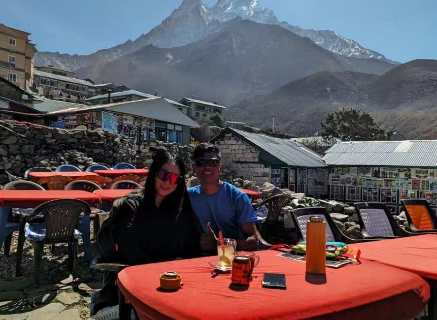 "Trekkers enjoying a sunny break at a local café in front of Mount Ama Dablam during Everest Base Camp trek, Nepal."