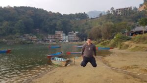Man jumping on by lakeside on Pokhara with background of colorful boats and Phewa Lake!
